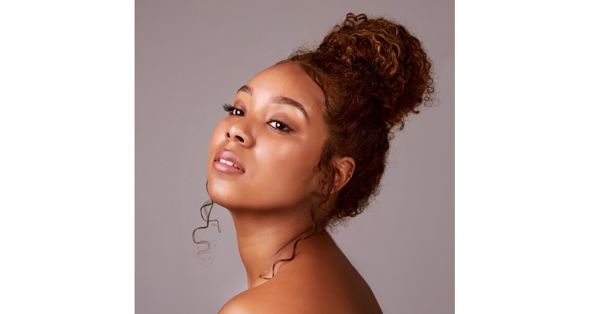mulher negra com cabelo acobreado com coque alto